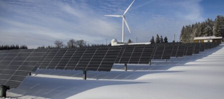 solar panels on snow with windmill under clear day sky